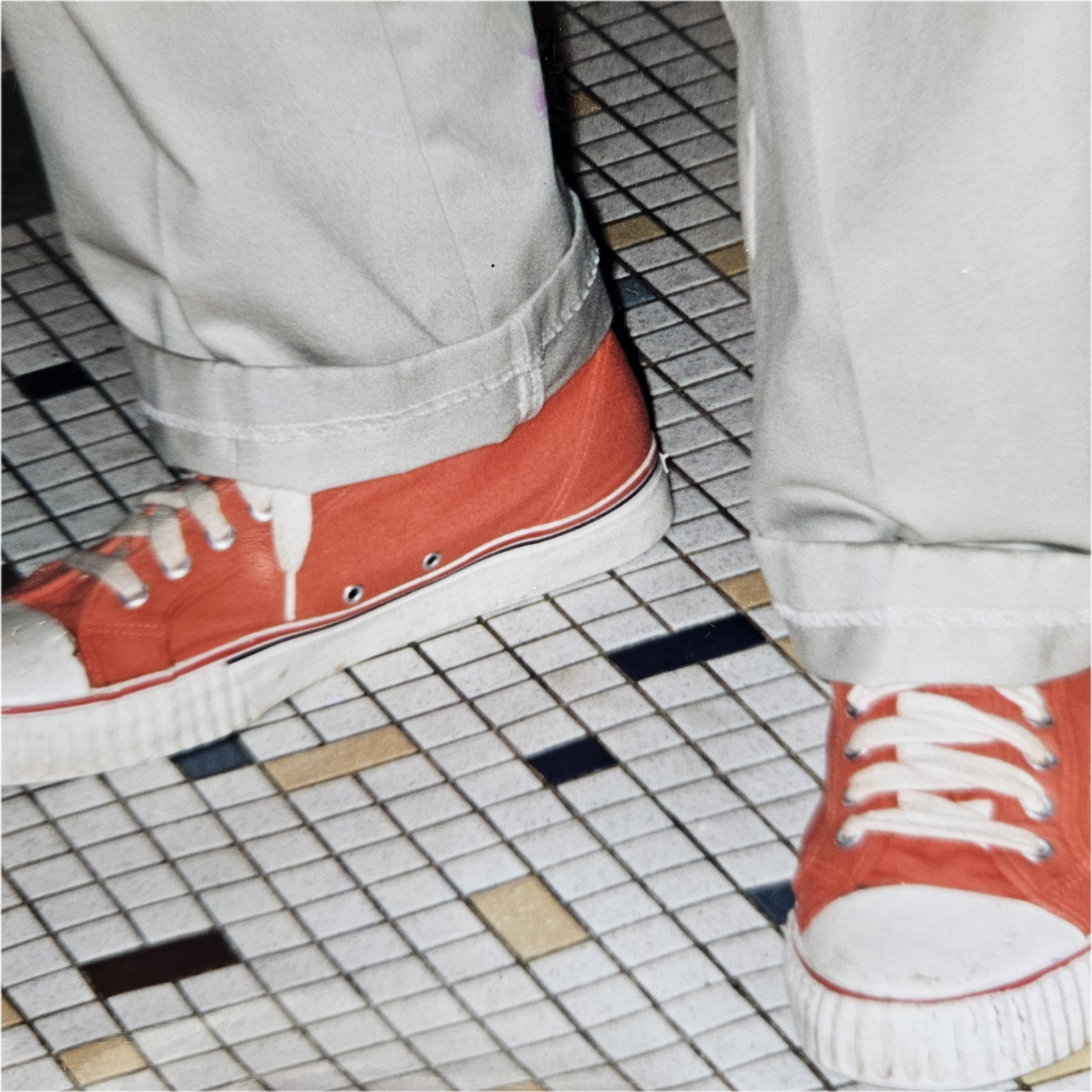 Dad wearing Orange Sneakers A person wearing red sneakers standing on tiled floor.