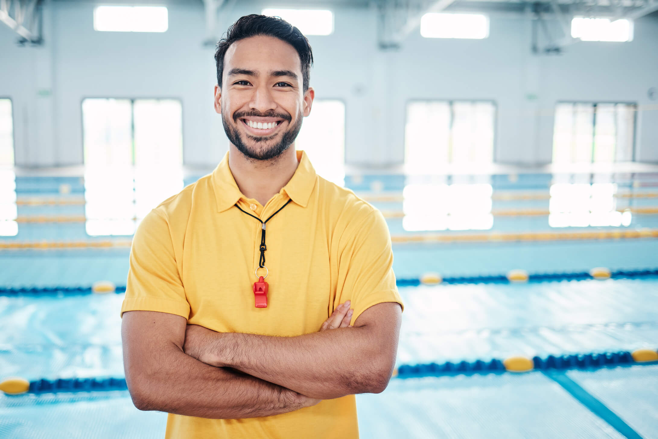 A man in yellow shirt standing next to pool.