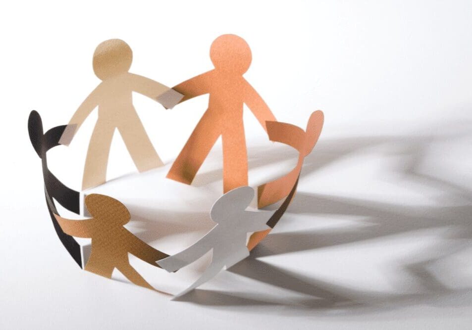 Paper cutouts of diverse human figures holding hands in a circle, casting shadows on a white surface.